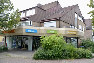 Haus der Kulturen Modernes Gebäude mit Schriftzug "Haus der Kulturen", umgeben von Bäumen und Pflanzen.
