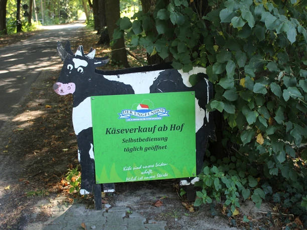 engelnhof-02-emsland-tourismus-christina-poll Holzkuh mit grünem Schild weist am Wegesrand auf den Käseverkauf mit Selbstbedienung hin.