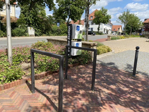 e-bike-ladestation_rathaus_cc_gemeinde-hagen-atw E-Bike-Ladestation mit Parkmöglichkeiten in einer grünen Umgebung.