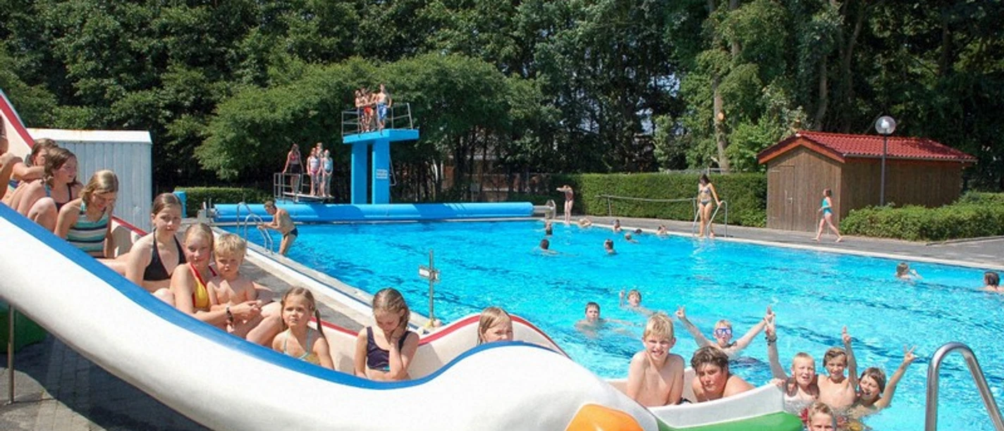 Freibad Lathen Kinder und Erwachsene genießen das Schwimmen und Rutschen im Freibad mit großer blauer Beckenanlage.
