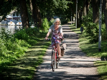 Radfahren Eine Frau fährt Fahrrad im Schatten der Bäume.