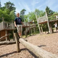 abenteuerspielplatz-bispingen-kinder Der Abenteuerspielplatz Bispingen zeigt lachende Kinder, die auf Holzspielgeräten balancieren und klettern, umgeben von Wald.