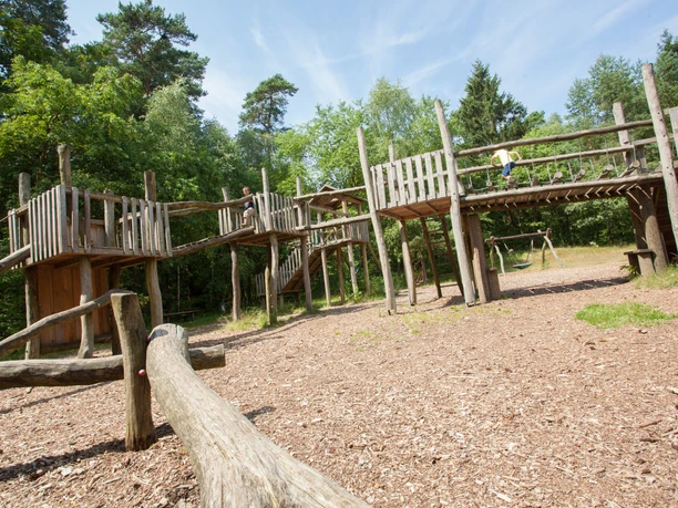 spielburg Adventure playground in a wooded area with wooden structures for climbing. Ideal for children.