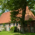 bispingen-ole-kerk Die alte Kirche in Bispingen aus Feld- und Backsteinen mit rotgedecktem Satteldach, umgeben von Grün.