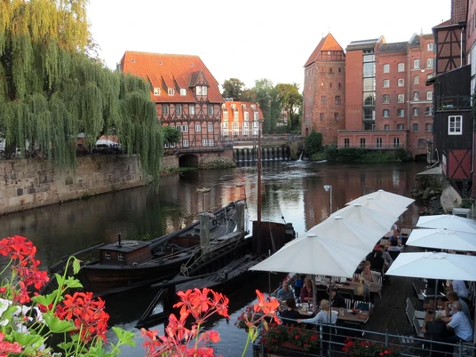 lüneburg-innenstadt Ein Holzboot liegt am Stadtgraben am Stint, umgeben von historischen Gebäuden und üppigem Grün.