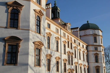 schloss-celle Das Bild zeigt Schloss Celle, ein historisches Bauwerk mit weißen Fassaden. Der blaue Himmel betont die Architektur, während die Sonne sanft Schatten wirft.