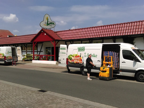 Gemüse- und Bauernmarkt Lüske Mitarbeiter lädt frische Waren aus Lieferwagen vor dem Gebäude des Gemüse- und Bauernmarkts Lüske.