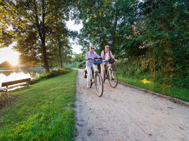 Fahrrad fahren Ein Paar fährt mit ihren Fahrrädern entlang eines Sees.