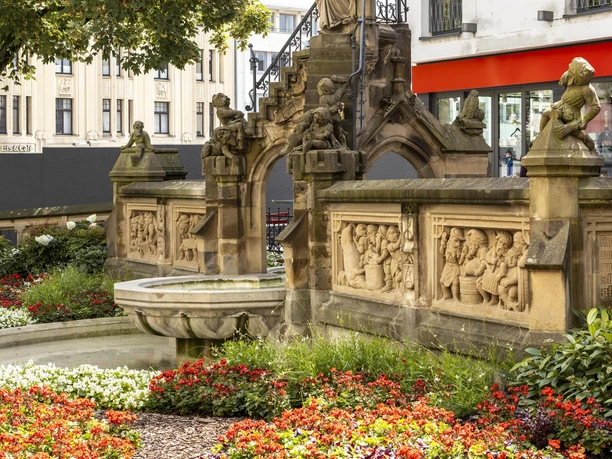Heinzelmaennchenbrunnen Der Heinzelmännchenbrunnen in Köln zeigt eine detailreiche Steinskulptur mit feinen Reliefs und Gärten.