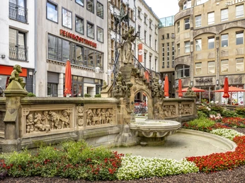 Pixies’ Fountain Ein kunstvoller Brunnen mit Skulpturen inmitten urbaner Umgebung.An artistic fountain with sculptures in an urban setting.