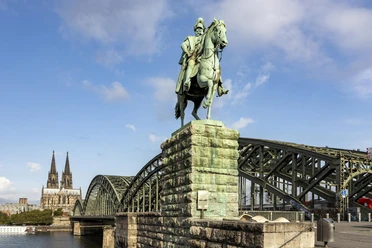 Equestrian statue of Kaiser Wilhelm I. A majestic equestrian statue of Kaiser Wilhelm I, with Cologne Cathedral and the Hohenzollern Bridge in the background.