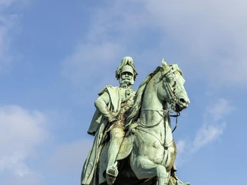 Equestrian statue of Kaiser Wilhelm I. Das Reiterstandbild von Kaiser Wilhelm I. zeigt eine beeindruckende Bronzefigur des Kaisers auf einem Pferd. Die Statue thront majestätisch auf einem hohen Steinsockel. Sie erhebt sich vor einem blauen Himmel und symbolisiert historische Bedeutung und Macht.The equestrian statue of Kaiser Wilhelm I shows an impressive bronze figure of the emperor on horseback. The statue is majestically enthroned on a high stone plinth. It rises against a blue sky and symbolizes historical significance and power.