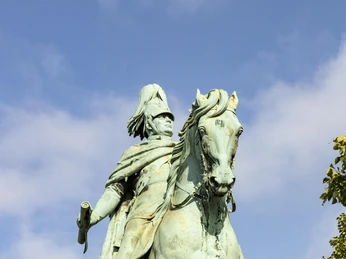 Reiterstandbild König Friedrich Wilhelm IV. Das Reiterstandbild von König Friedrich Wilhelm IV. in Köln zeigt die bronzene Figur des Monarchen auf einem majestätischen Pferd, umrahmt von grünen Bäumen und einem strahlend blauen Himmel.The equestrian statue of King Frederick William IV in Cologne shows the bronze figure of the monarch on a majestic horse, framed by green trees and a bright blue sky.