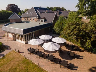 Hotel Preyt Aussenterrasse.jpg Hotelterrasse mit gepflastertem Boden, Sonnenschirmen und schwarzen Tischen unter freiem Himmel.