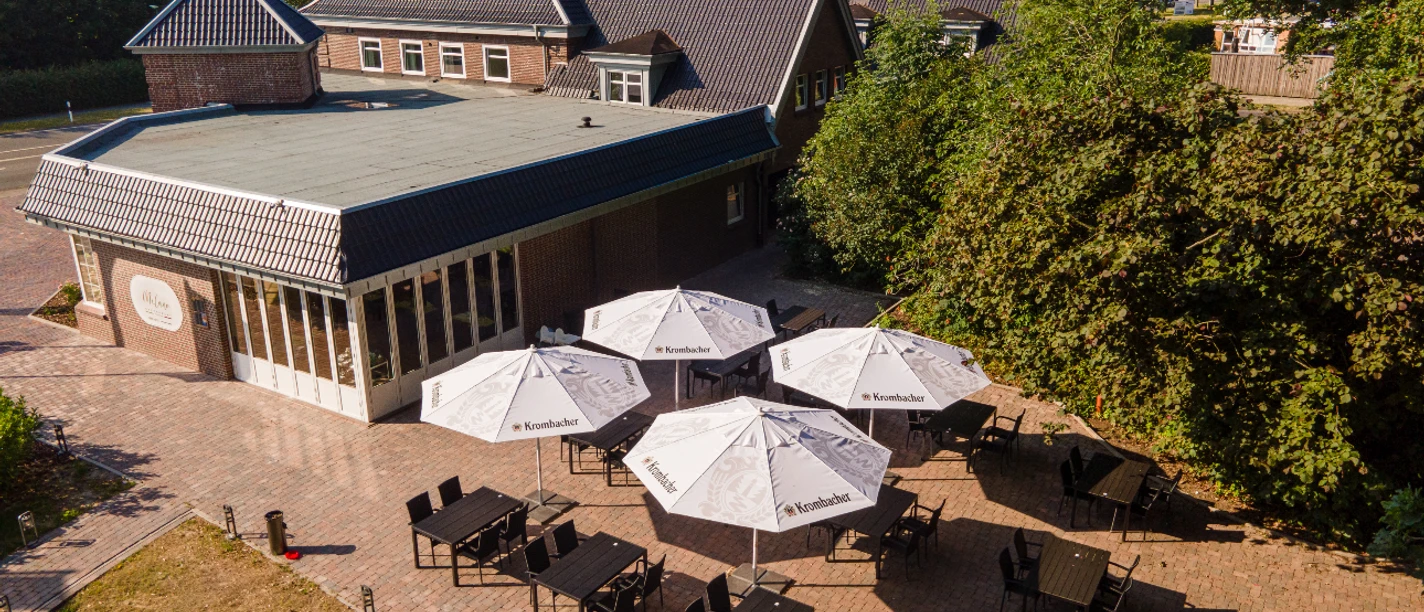 Hotel Preyt Aussenterrasse.jpg Hotelterrasse mit gepflastertem Boden, Sonnenschirmen und schwarzen Tischen unter freiem Himmel.