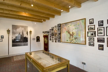 Wahner Zimmer Ausstellungsraum mit historischen Fotos, Karte, Vitrine und hölzerner Decke im Museumsdorf.