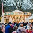 Christkindlesmarkt_GesUndTourismus Horn-Bad Meinberg GmbH_Nils Klöpper1.jpg Ein nostalgisches Karussell auf einem Weihnachtsmarkt, umgeben von Menschen in Winterkleidung.