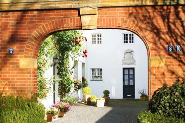 Zeughaus Meppen Roter Torbogen mit Blick in einen begrünten Innenhof und weißer Fassade des historischen Zeughauses.