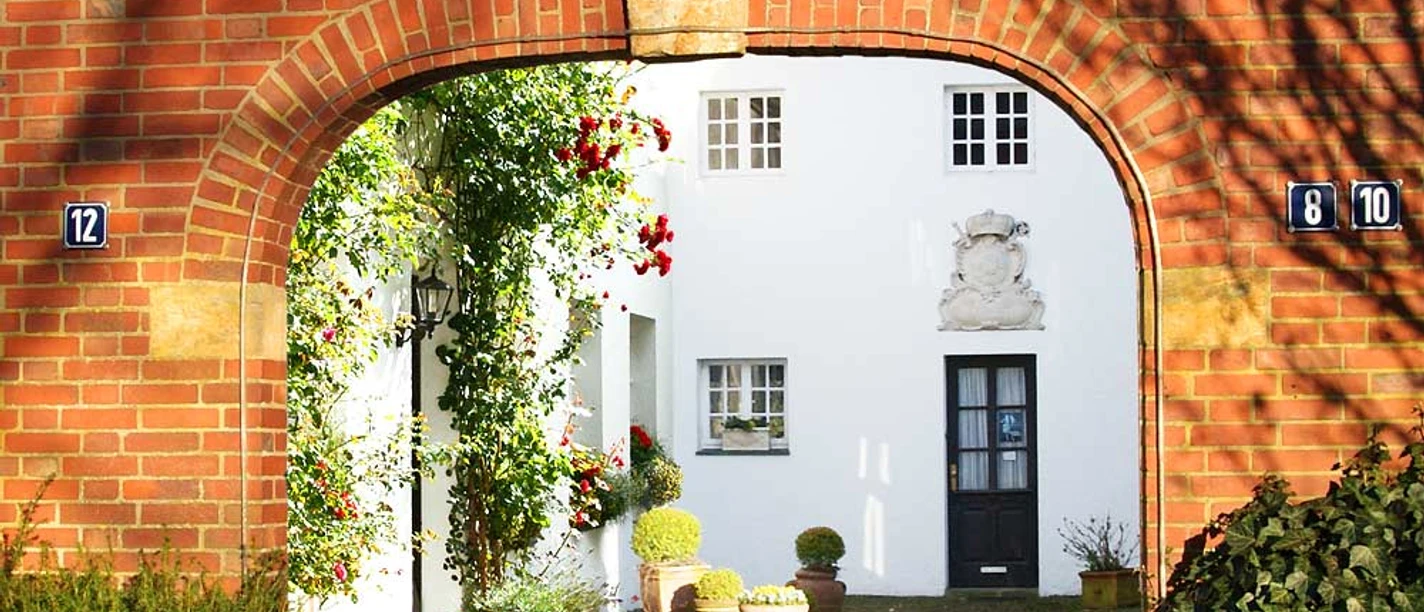 Zeughaus Meppen Roter Torbogen mit Blick in einen begrünten Innenhof und weißer Fassade des historischen Zeughauses.