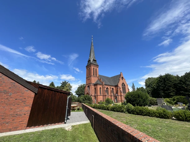 St. Jakobi-Kirche zu Wittlohe Die rote Backstein-St. Jakobi-Kirche in Wittlohe erhebt sich vor einem klaren blauen Himmel.