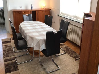 Esszimmer Esszimmer mit einem rechteckigen Tisch, sechs schwarzen Stühlen und Schränken, Tageslicht dringt herein.