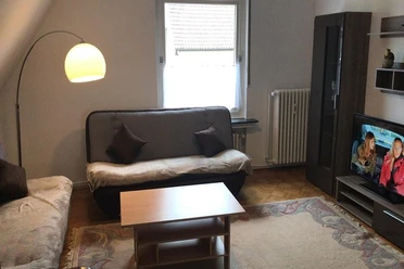 Wohnbereich Wohnzimmer mit zwei Sofas, hellem Teppich, Fernseher an der Wand und einer Stehlampe.
