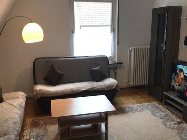 Wohnbereich Wohnzimmer mit zwei Sofas, hellem Teppich, Fernseher an der Wand und einer Stehlampe.