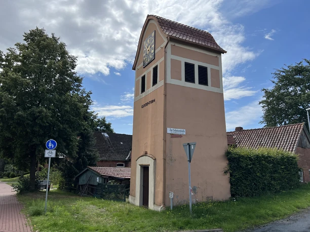 Ein historischer Glockenturm mit einem roten Ziegeldach und einer Uhr thront in Neddenaverbergen.