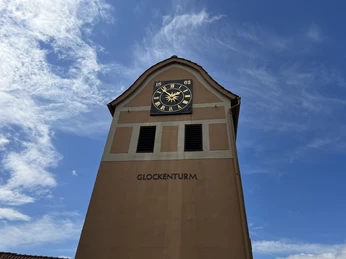 Der Glockenturm in Neddenaverbergen erhebt sich gegen einen klaren, blauen Himmel mit zarten Wolken.