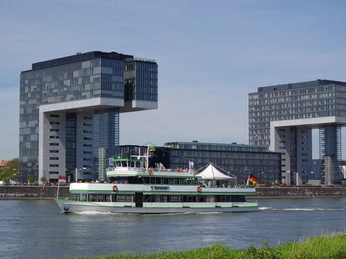 Kölntourist passenger boat service Blick auf den Rhein in Köln mit einem vorbeifahrenden Ausflugsschiff vor den markanten Kranhäusern.View of the Rhine in Cologne with a passing excursion boat in front of the striking crane buildings.