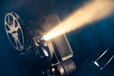 Schmalfilm- Museum Alter Filmprojektor strahlt Licht durch den Raum und setzt Filmrollen in Bewegung.