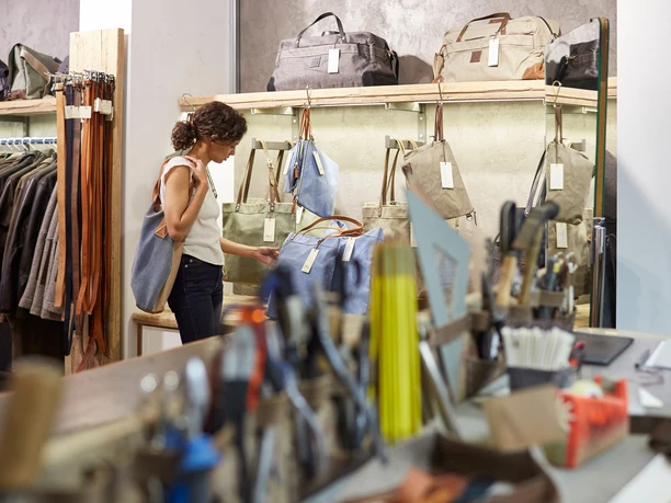 Belgian Quarter The image shows a person shopping in a leather goods store in Cologne and looking at bags.