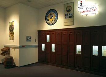 Gründer- und Unternehmermuseum Im Gründer- und Unternehmermuseum sind historische Bierwerbeschilder und eine locker stehende Holzmöbelvitrine zu sehen.