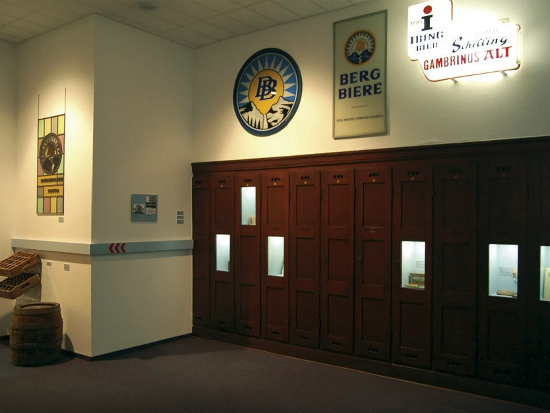 Gründer- und Unternehmermuseum Im Gründer- und Unternehmermuseum sind historische Bierwerbeschilder und eine locker stehende Holzmöbelvitrine zu sehen.