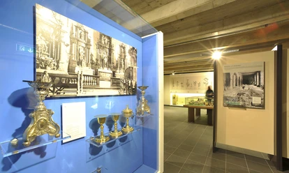Museum im Kloster Saarn Ausstellungsstück im Museum im Kloster Saarn mit historischen Kelchen und schwarz-weißen Fotografien.