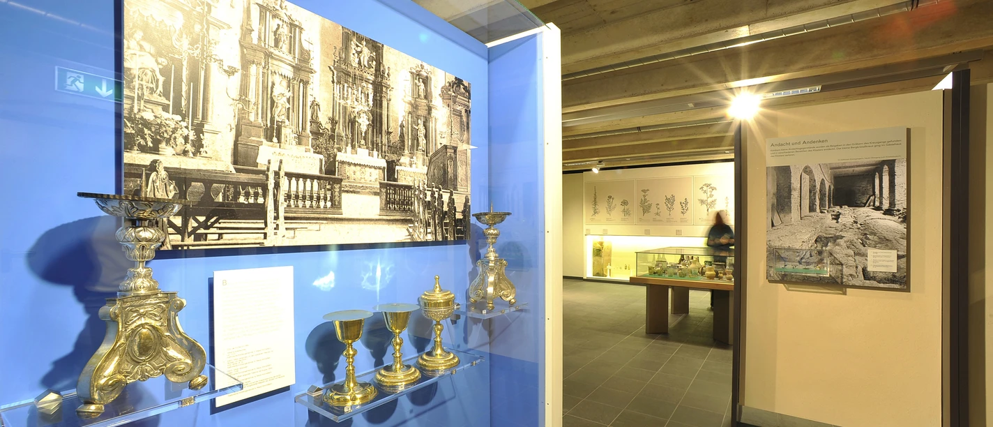 Museum im Kloster Saarn Ausstellungsstück im Museum im Kloster Saarn mit historischen Kelchen und schwarz-weißen Fotografien.