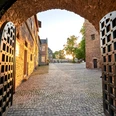 Schloß Broich, Mülheim an der Ruhr Blick durch ein geöffnetes Burgtor auf den gepflasterten Innenhof von Schloss Broich bei Sonnenuntergang.