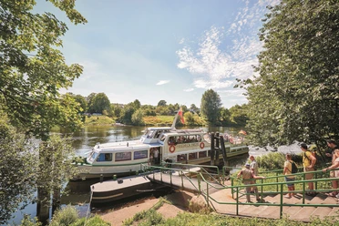 Schiffsanleger Kettwig, Essen Ein Fahrgastschiff auf einem Fluss an einem Anleger in grüner Umgebung bei sonnigem Wetter