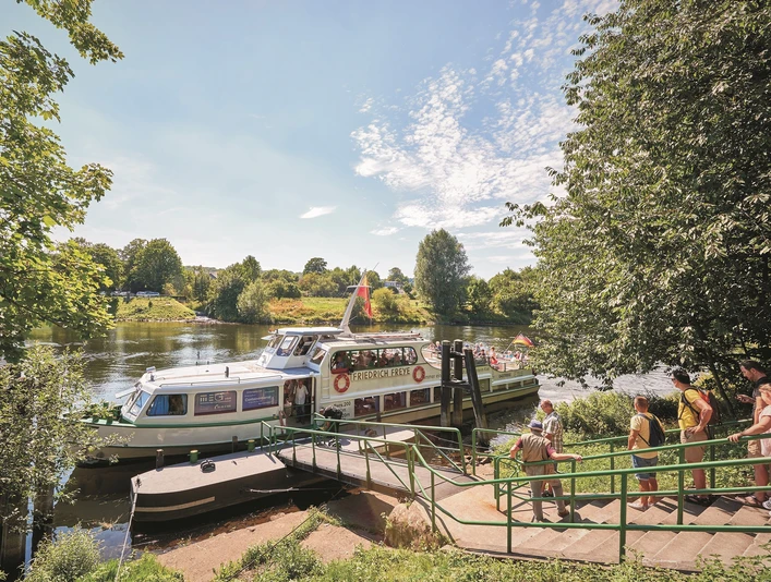 Schiffsanleger Kettwig, Essen Ein Fahrgastschiff auf einem Fluss an einem Anleger in grüner Umgebung bei sonnigem Wetter