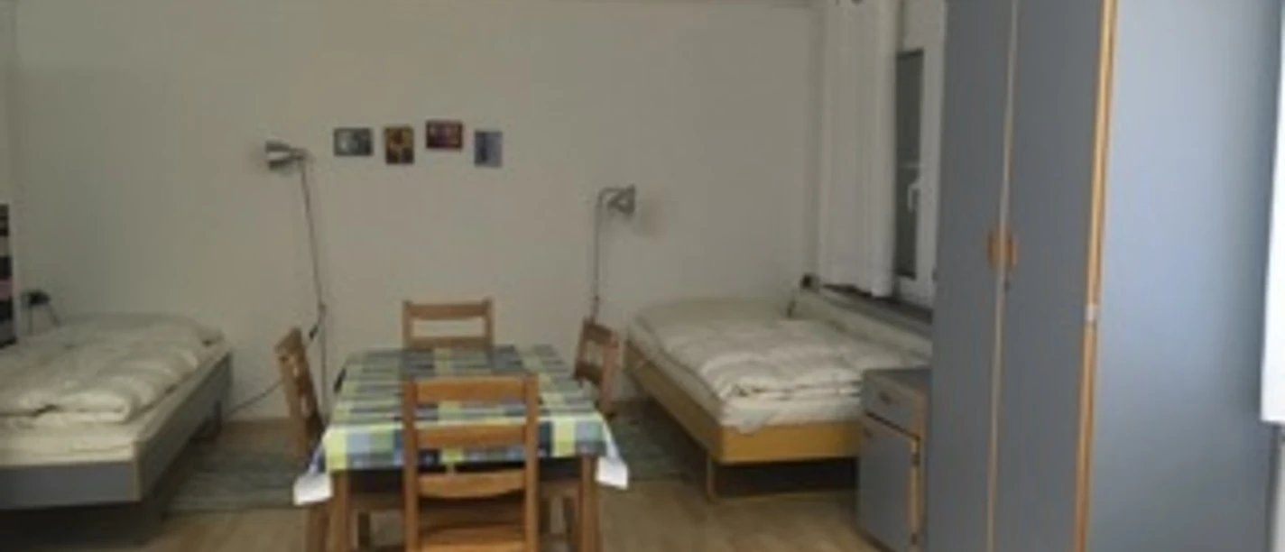 Monteurzimmer mit mehreren Betten, einem Tisch und Stühlen