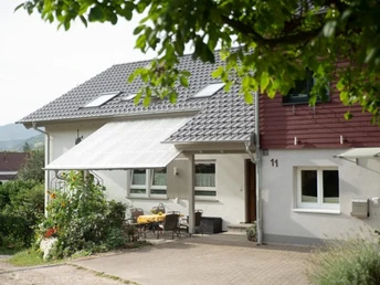 Freisitz mit Steinbelag, im Hintergrund ein weißes Haus mit grauem Dach