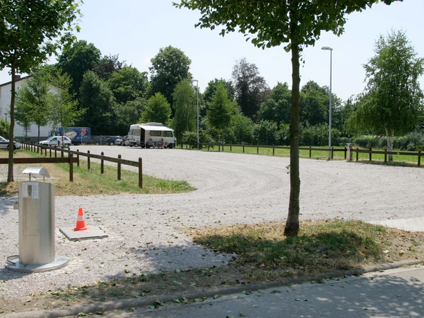 Wohnmobilstellplatz mit Schotterweg und Bäumen. Wasserversorgungseinrichtung und Schmutzwasser-Entsorgungsanlage