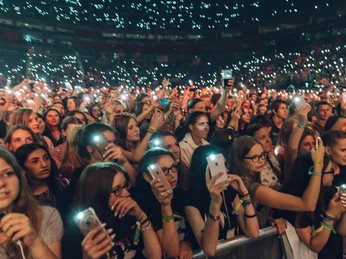 Lanxess Arena Menschenmenge bei einem Konzert in der Lanxess-Arena, viele halten leuchtende Smartphones in die Höhe.Crowd at a concert in the Lanxess Arena, many holding up glowing smartphones.