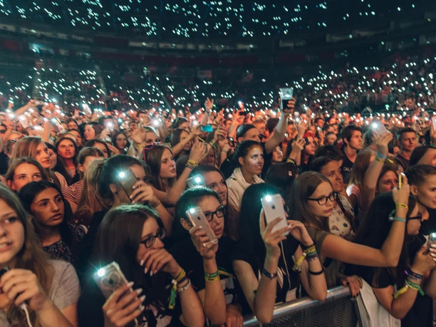 Lanxess Arena Menschenmenge bei einem Konzert in der Lanxess-Arena, viele halten leuchtende Smartphones in die Höhe.
