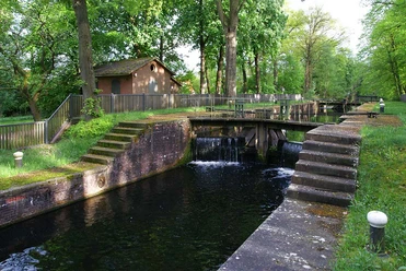 Koppelschleuse Historische Schleusenanlage mit Backsteinhaus, Wasserlauf und von Bäumen gesäumtem Grünbereich
