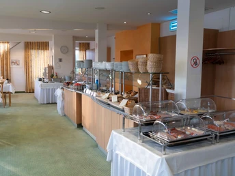 Frühstücksbereich mit gedeckten Tischen und Stühlen, Blick auf das Büffet