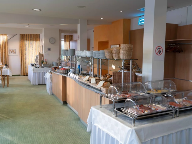 Frühstücksbereich mit gedeckten Tischen und Stühlen, Blick auf das Büffet