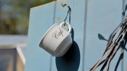 Kaffeegenuss in Dithmarschen Weiße Tasse mit Schriftzug an blauer Wand hängend
