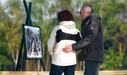 Otto-Pankok-Malerweg Zwei Personen betrachten im Grünen eine Freilufttafel mit einem Kunstwerk von Otto Pankok.