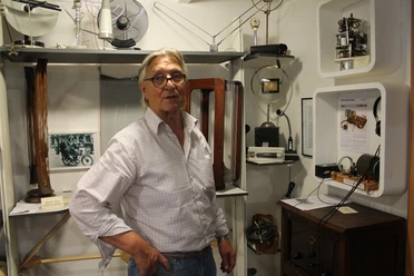 Rudis Rundfunk- und Maler-Museum Ein älterer Mann steht in einem Ausstellungsraum mit historischen Rundfunkgeräten und Technikexponaten.